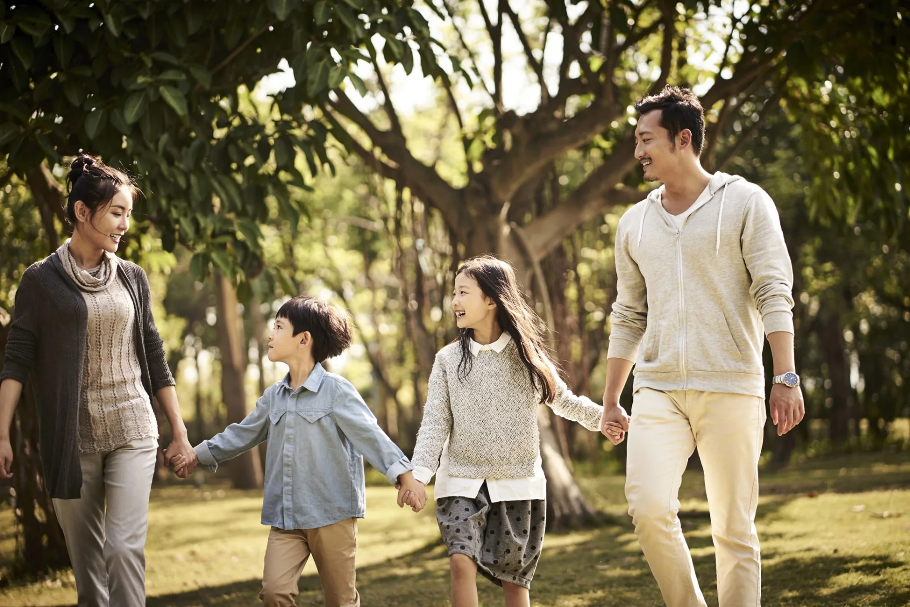 Happy nuclear family walking hands in hands in a park